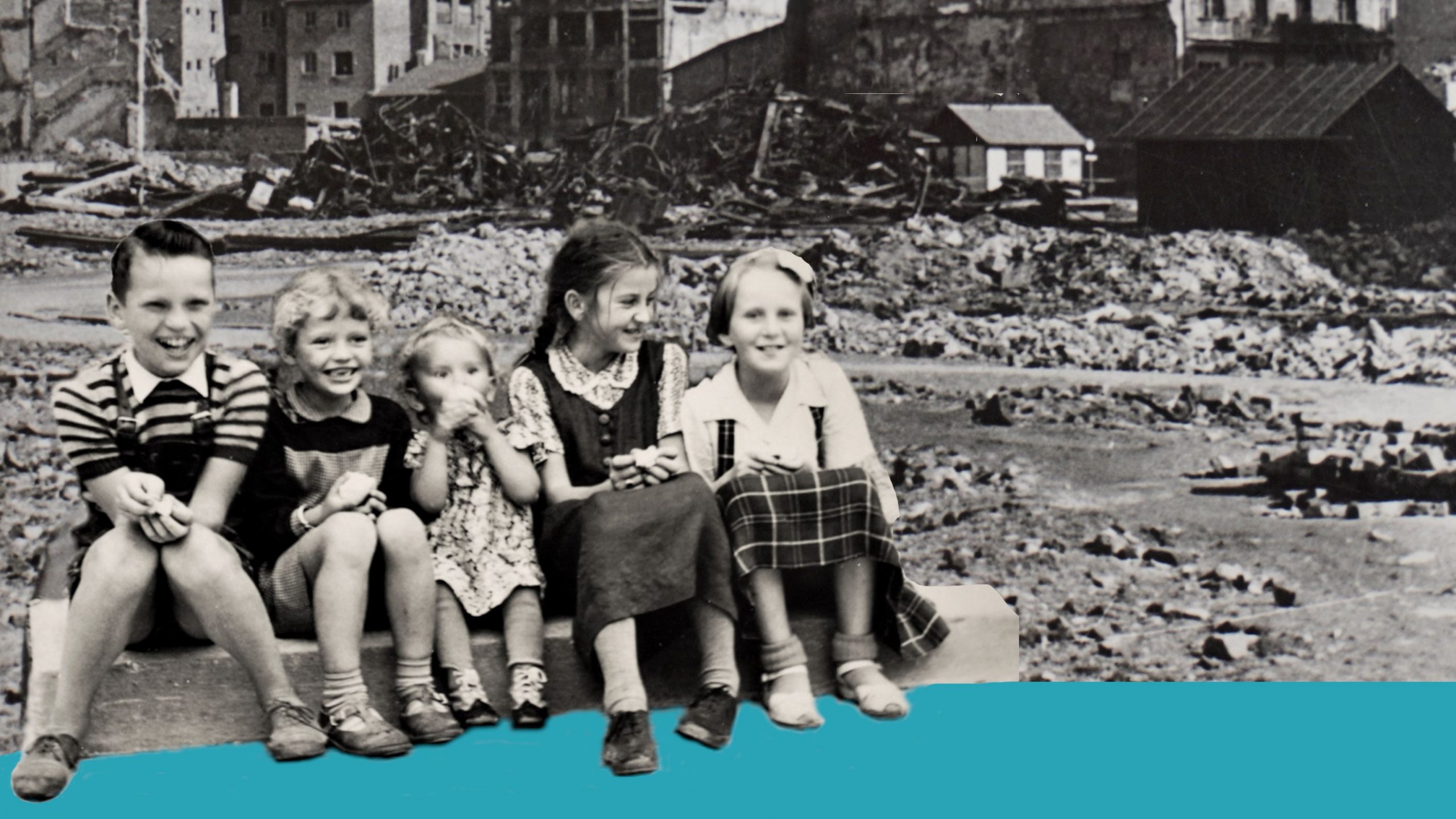 Kinder sitzen vor Trümmern